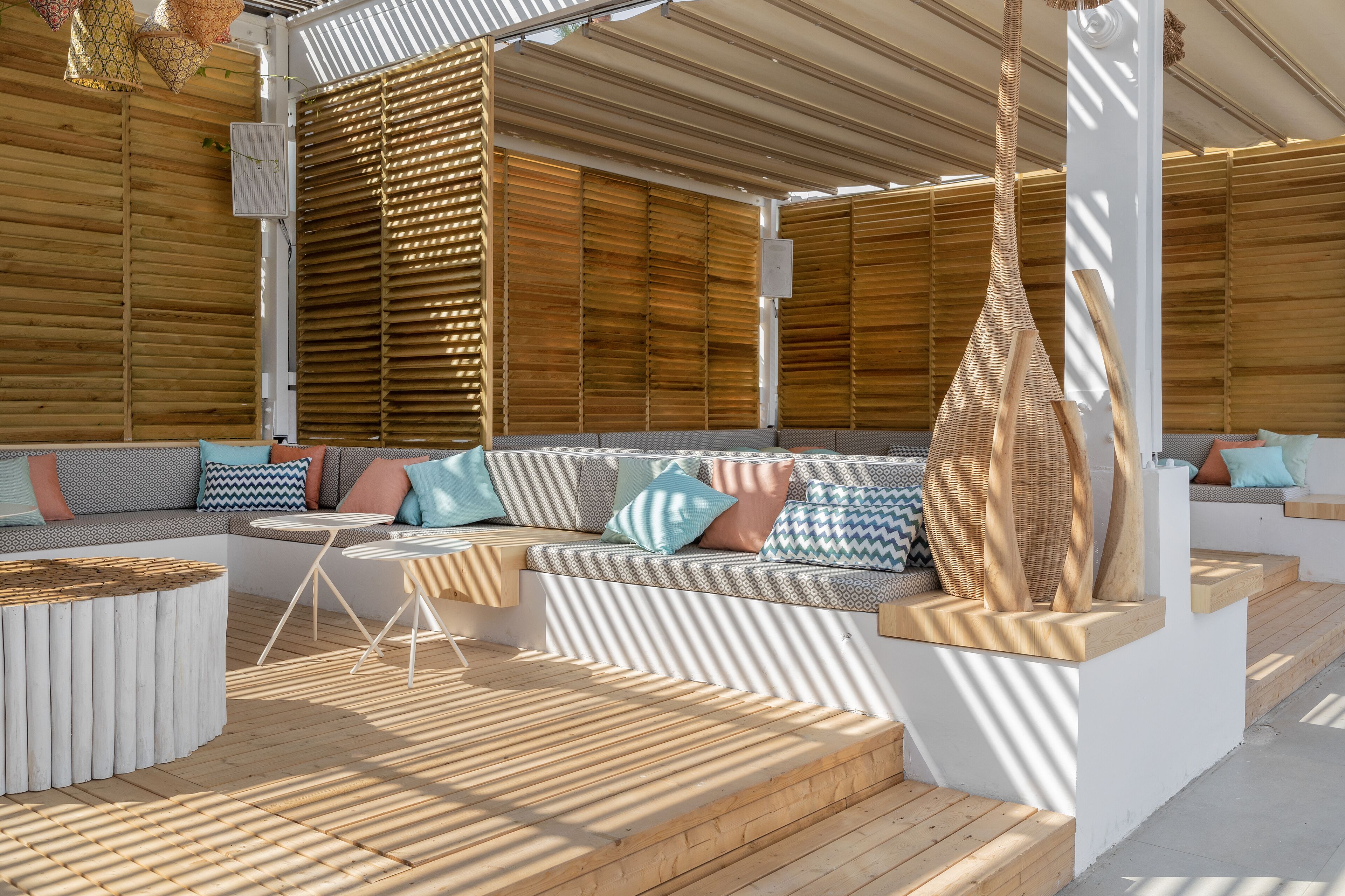A modern outdoor seating area with a wooden bench, cushioned seating, and a small table.