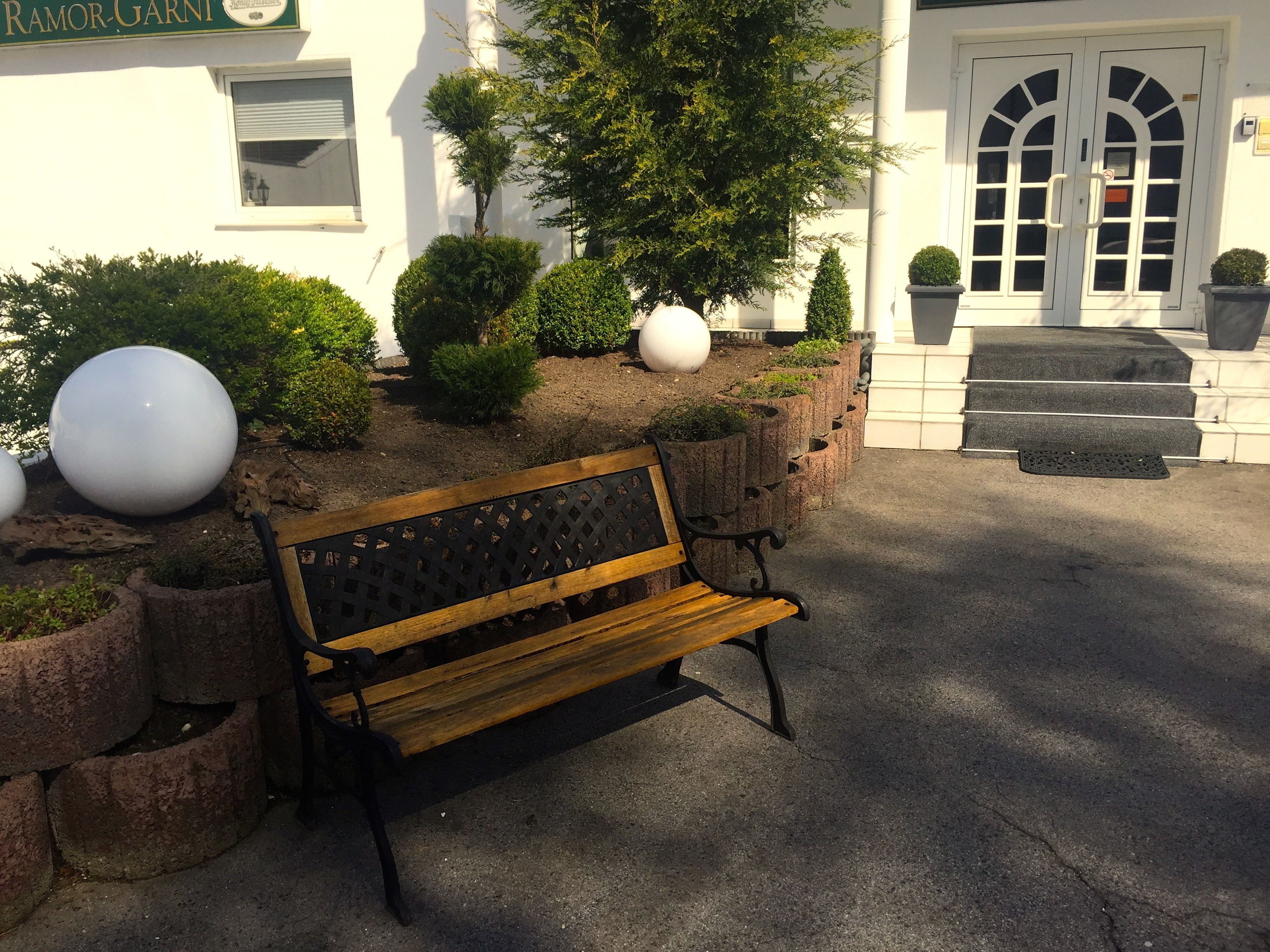 A bench in a landscaped area with a white building in the background.