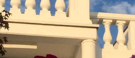 A white building with a balcony and a lion statue.