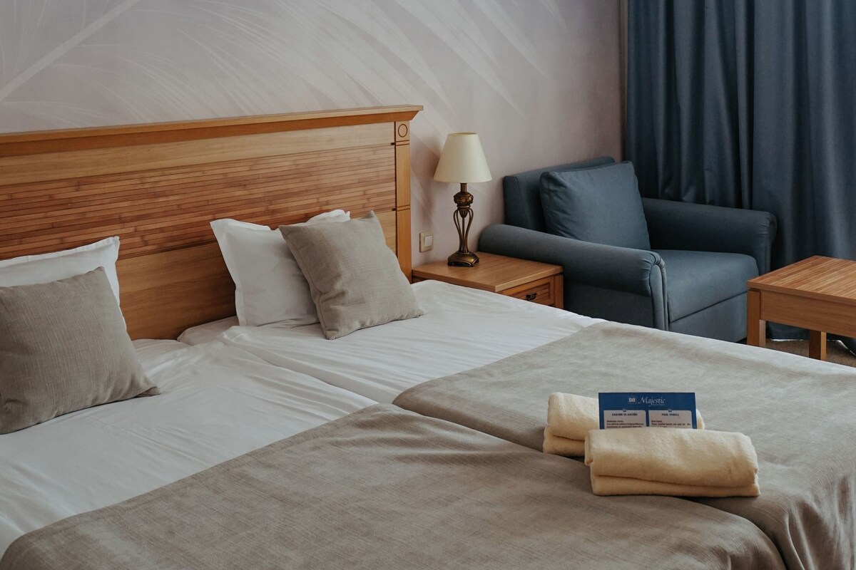Een hotelkamer met een bed, een stoel, een nachtkastje en een lamp.