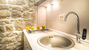 A kitchen with a stone wall, a stainless steel sink, and a modern faucet.