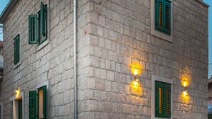A stone building with green shutters and exterior lighting.