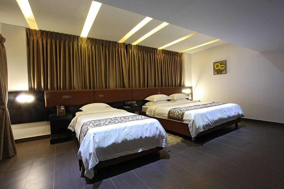 Habitación de hotel con dos camas, un ventanal grande con cortinas y un diseño moderno en el techo.
