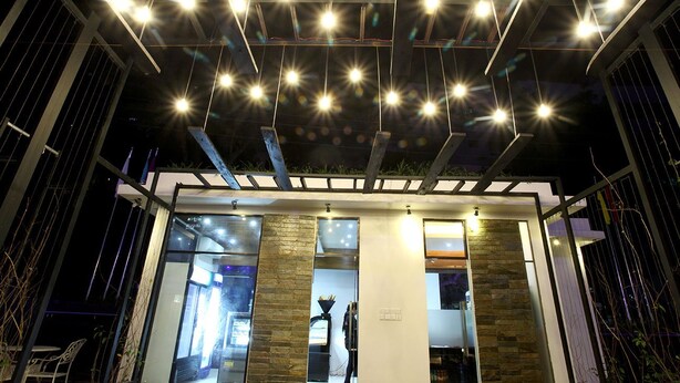 Un edificio moderno con fachada de vidrio, una columna de piedra y una serie de luces en el techo.