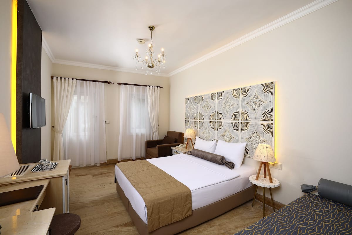 A hotel room with a bed, bedside table, lamp, and a decorative wall panel.