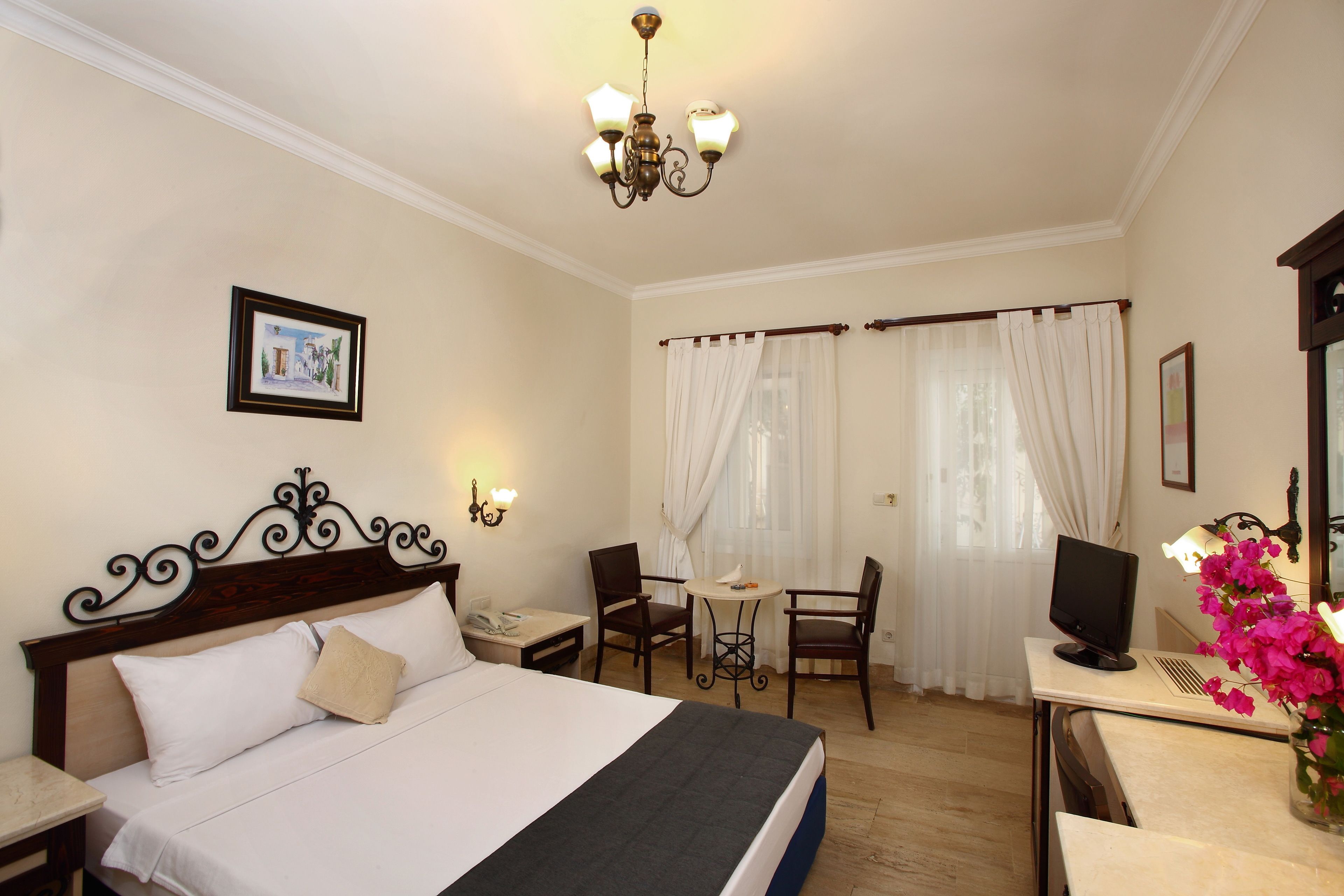 A hotel room with a bed, a desk, a chair, a television, and a window with curtains.