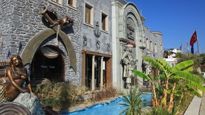 A stone building with a pool, statues, and a flag. - Cactus Fleur Bay Resort - All inclusive (Bodrum)