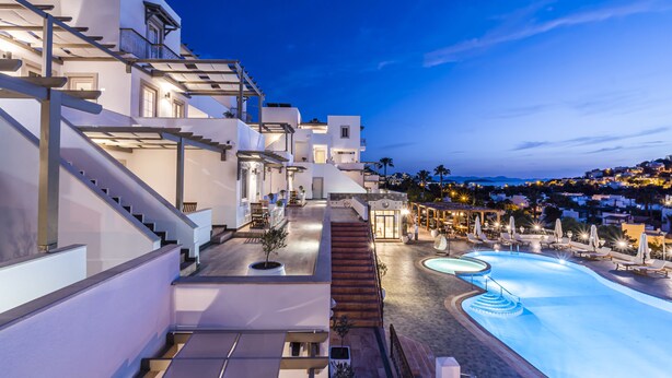 Un hotel moderno con piscina en la azotea, zona de estar exterior y una escalera que lleva a los pisos superiores.