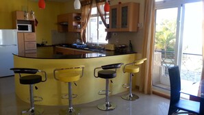 A kitchen with a central island, bar stools, and a refrigerator.