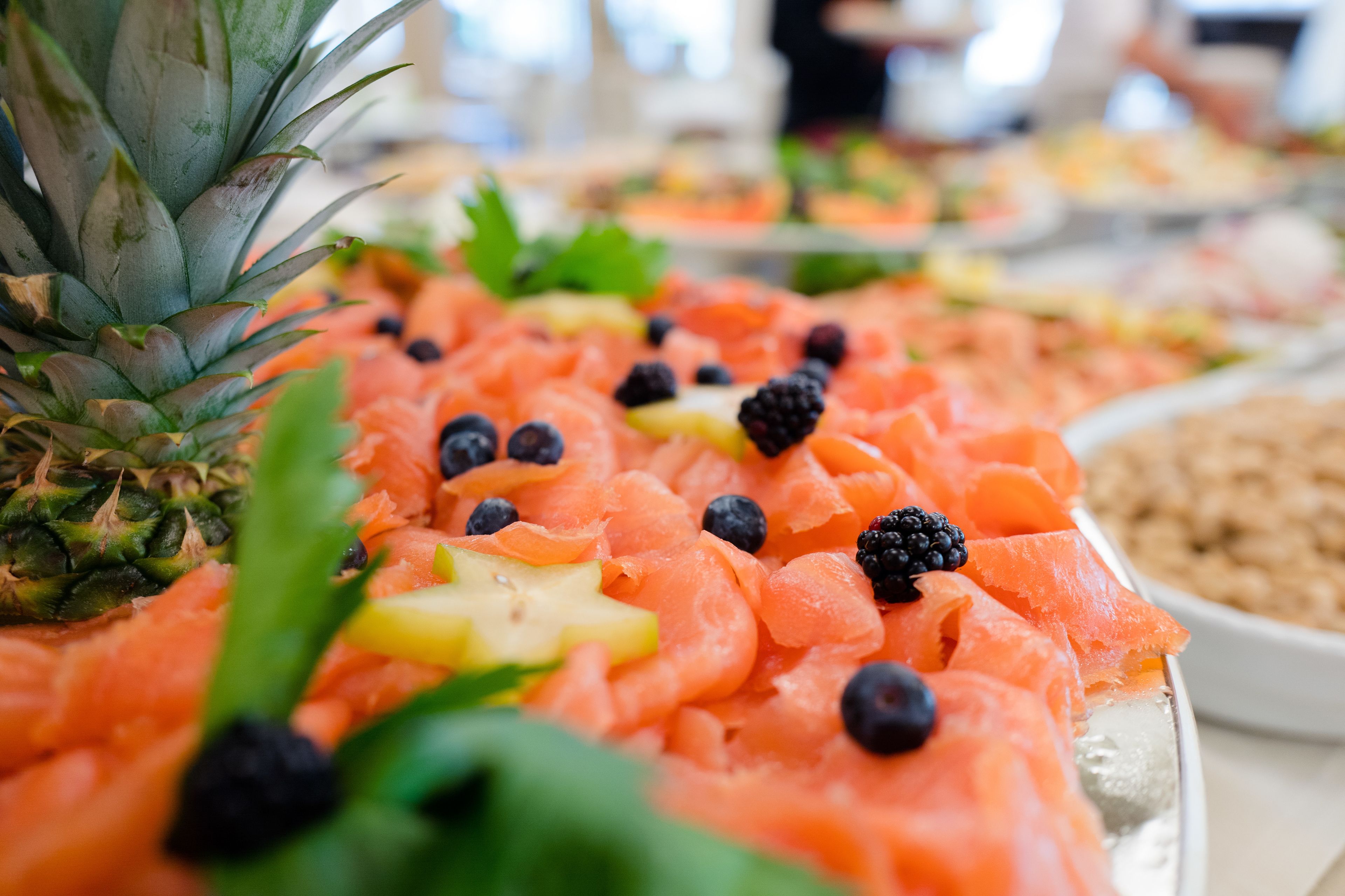A platter of smoked salmon garnished with blackberries and pineapple.