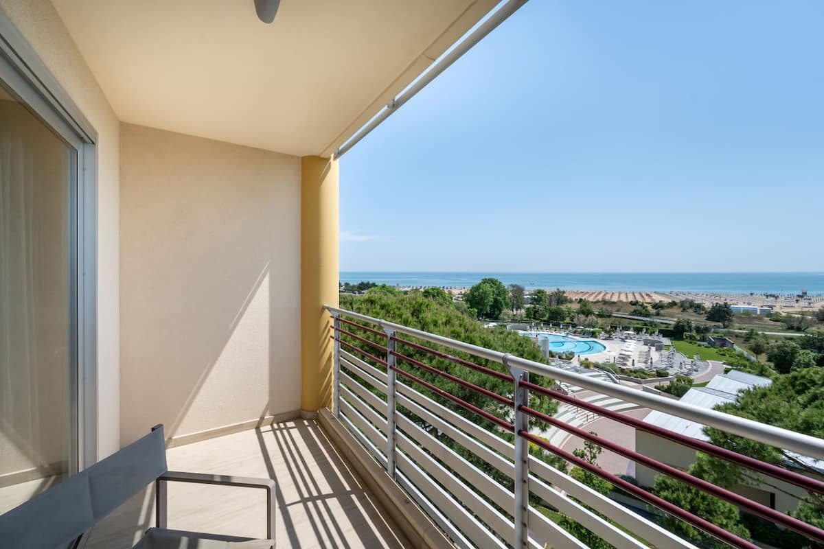 Een balkon met uitzicht op een strand en een zwembad.