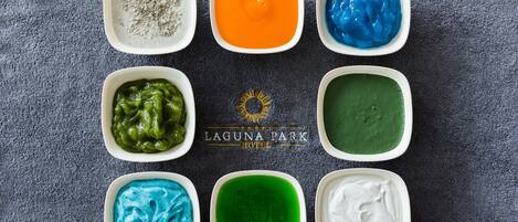 Eight bowls of colorful dips arranged on a table.