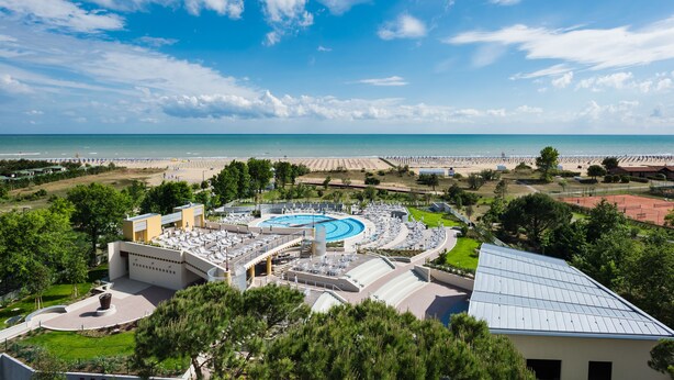 Ein Resort mit Schwimmbad, Zugang zum Strand und einem großzügigen Gebäude mit kreisförmiger Gestaltung.