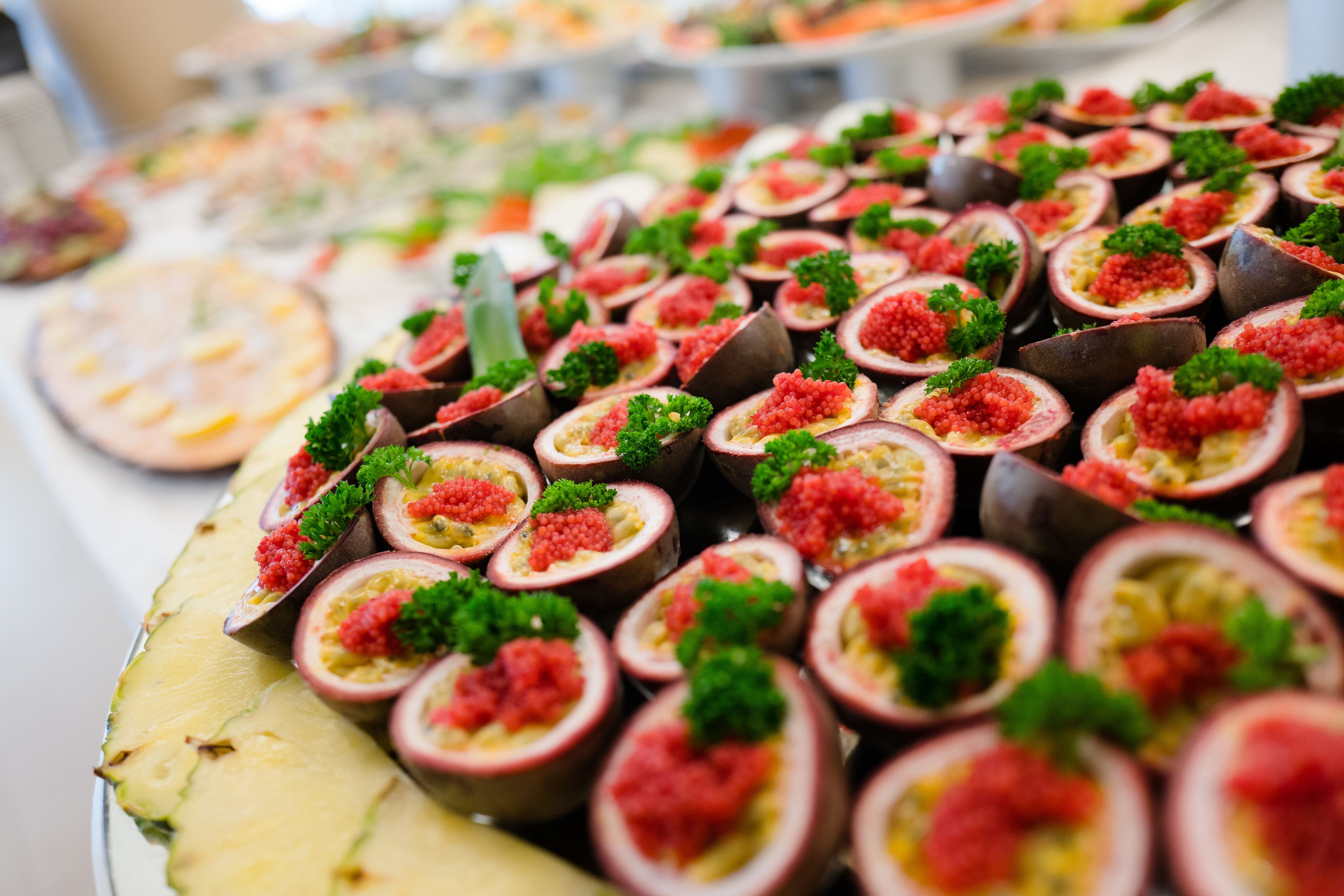 En buffet med et udvalg af mad, herunder et område med skåret frugt og grøntsager pyntet med krydderurter.
