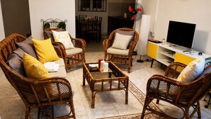 Una sala de estar con muebles de mimbre, un comedor y un televisor.