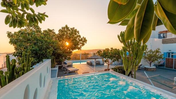 A swimming pool with a view of the sunset, surrounded by greenery and lounge chairs. - La Stella Stay (Mykonos)