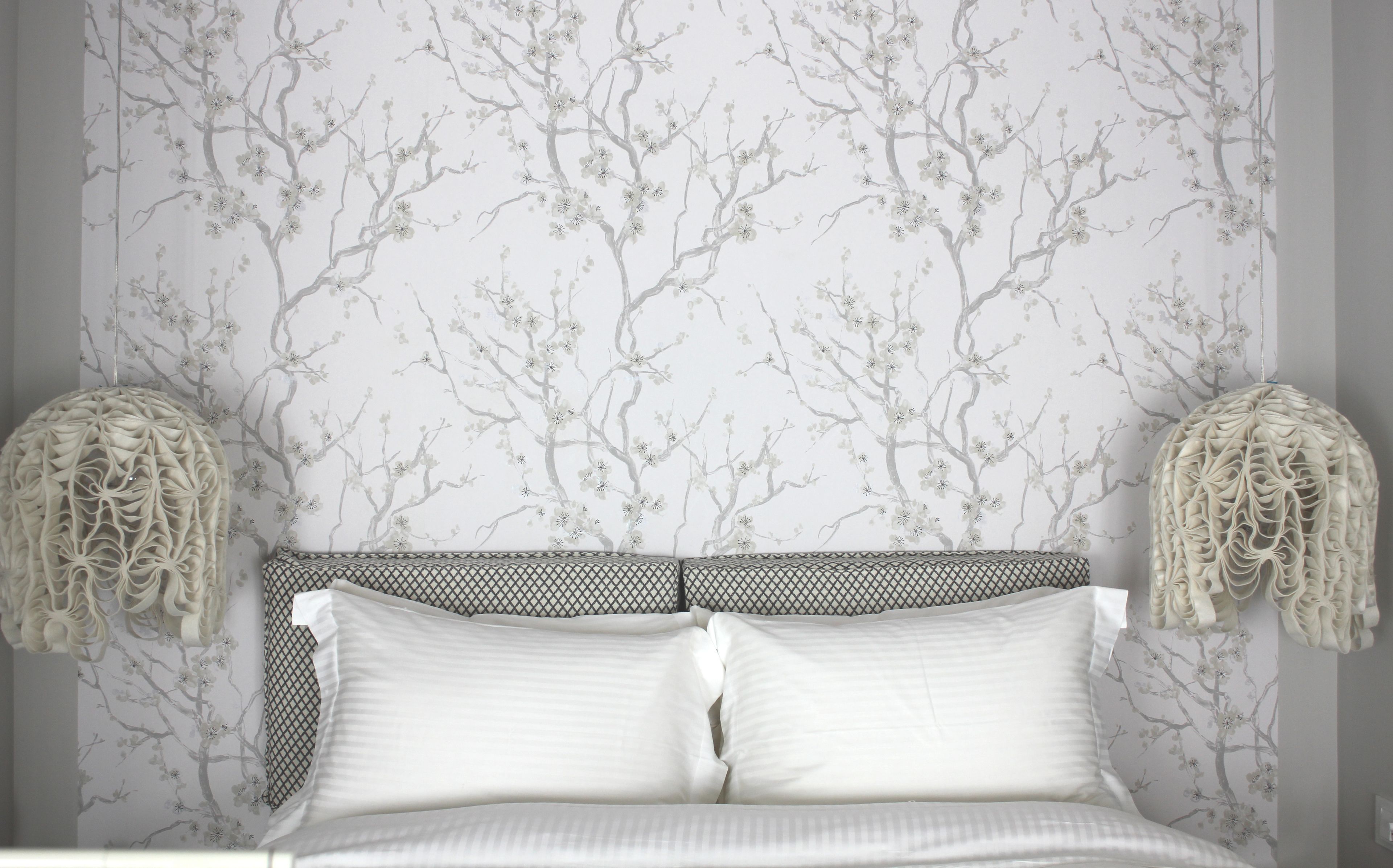 Un dormitorio con una cama, dos lámparas de pared y un estampado floral en el papel tapiz.