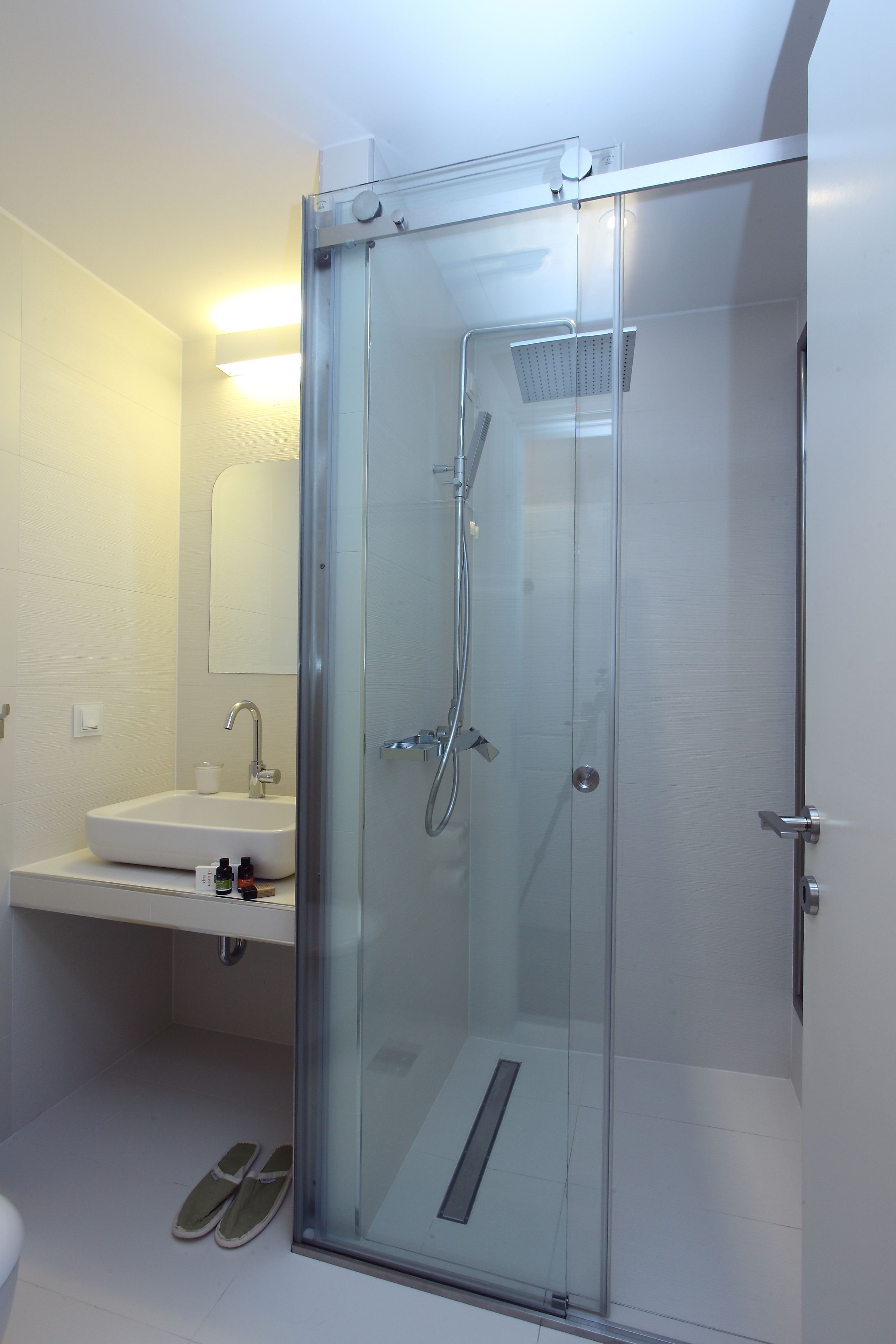 Ein modernes Badezimmer mit einer gläsernen Duschkabine, einem Waschbecken und einem Spiegel.