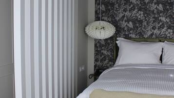 A bedroom with a bed, a bedside table with a tray of breakfast items, a hanging light fixture, and a striped door.