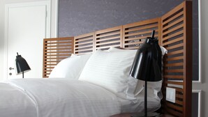 A neatly made bed with white linens, a wooden headboard, and a black desk lamp beside it. - Hotel Metropolis (Ioannina)