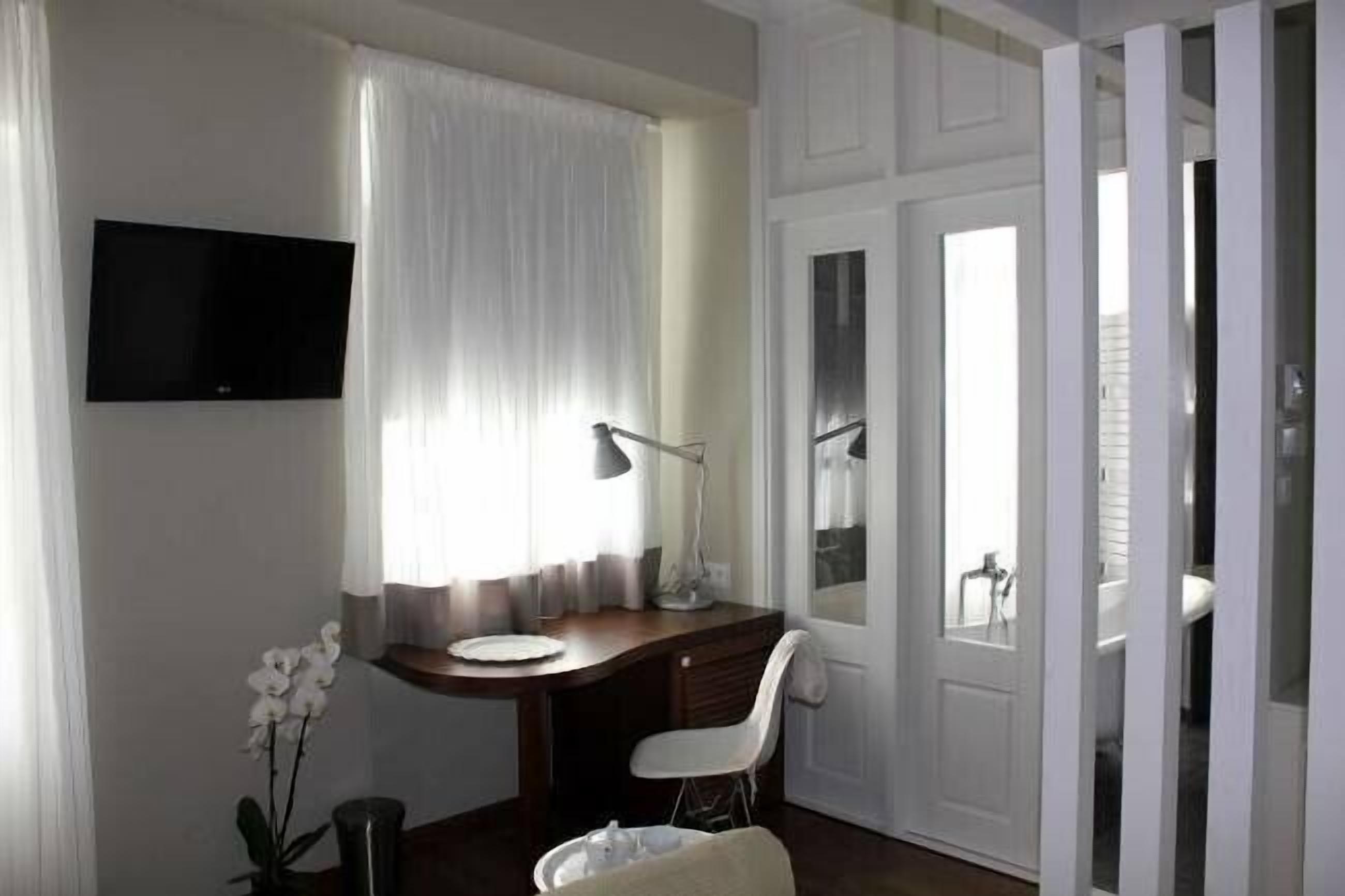 Ein Hotelzimmer mit Schreibtisch, Stuhl und einem an der Wand befestigten Fernseher.