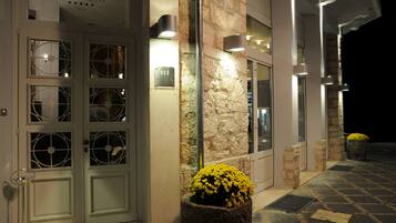 A hotel entrance with double doors, a stone wall, and a potted yellow flower.