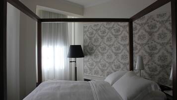 A hotel room with a large bed, a nightstand, a lamp, and a patterned wallpaper.