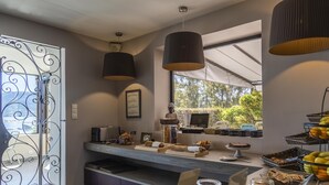 A modern kitchen with a buffet setup, including various food items and a coffee station. - Hôtel Shegara (Porto-Vecchio)