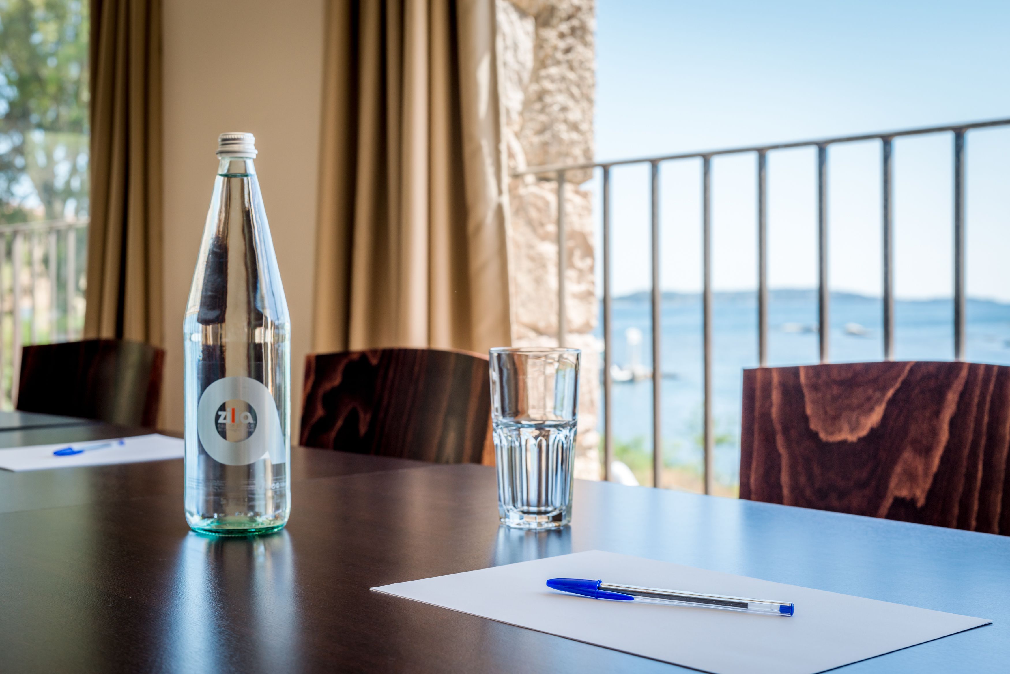 Ein Tisch mit einer Flasche, einem Glas und einem Stift, mit Blick auf eine schöne Aussicht.