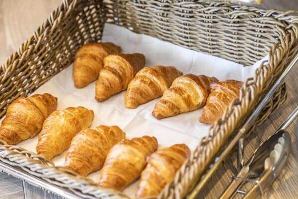 Una cesta de mimbre con varios croissants sobre un forro de papel blanco.