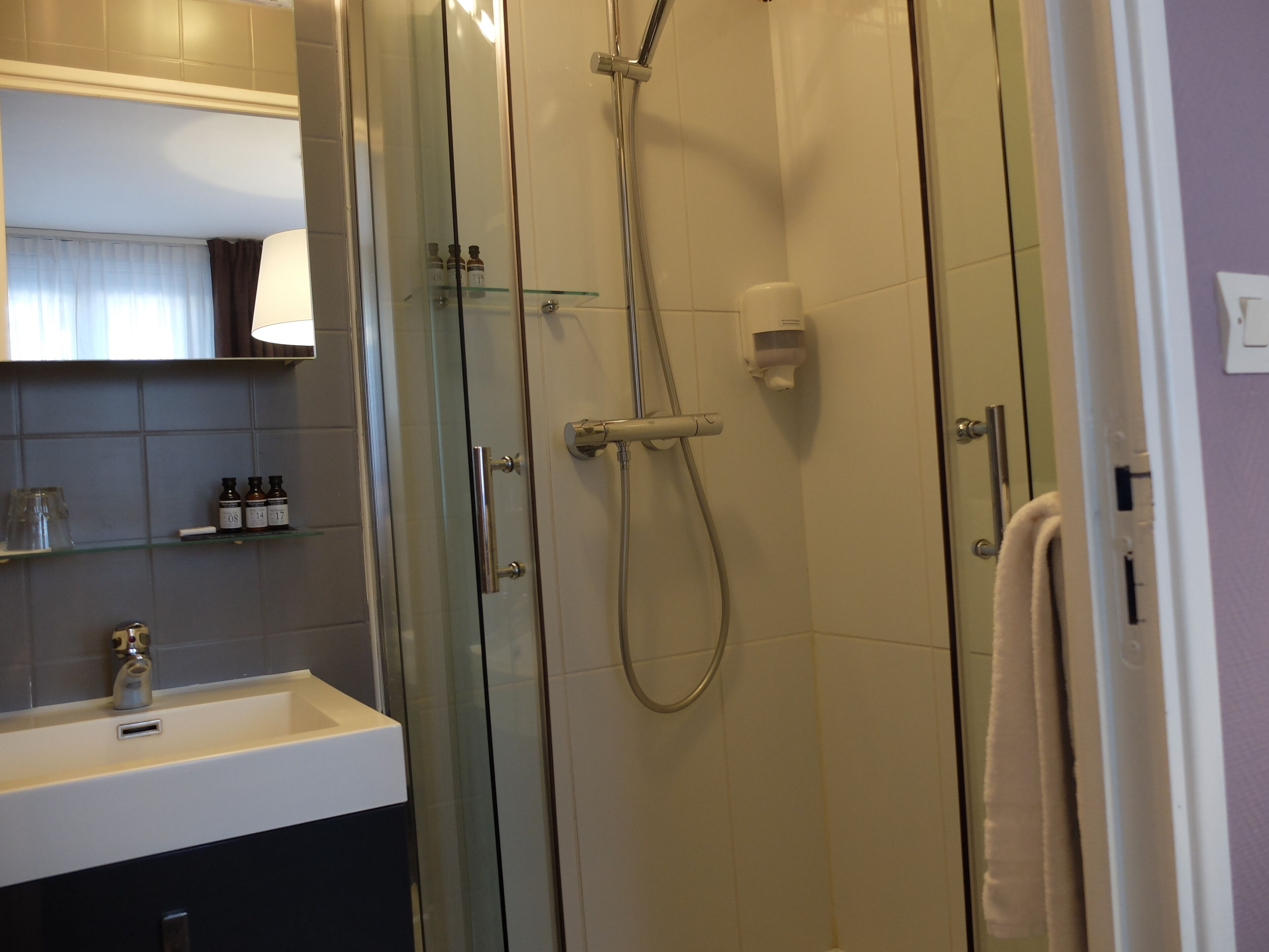 Une salle de bain moderne avec une douche à parois de verre, un lavabo blanc et un miroir au-dessus du lavabo.