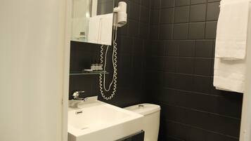 A bathroom with a white sink, a toilet, and a glass shower enclosure.