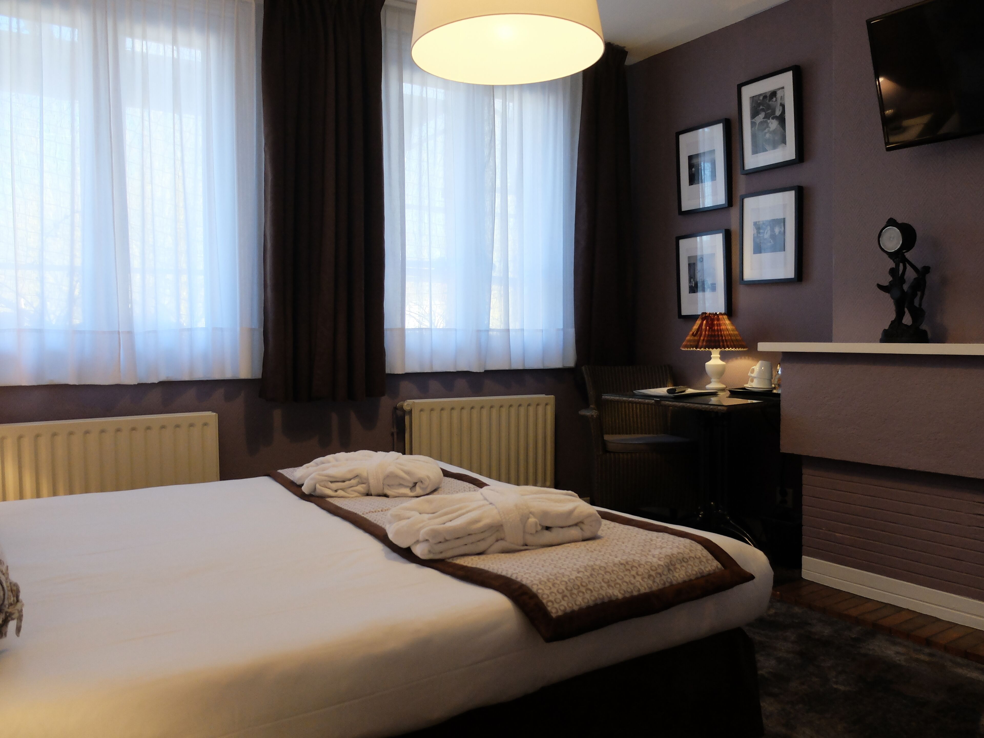 Een hotelkamer met een bed, een bureau, een stoel, een lamp en een open haard.