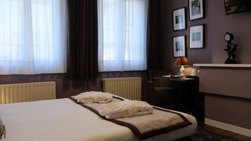 Een hotelkamer met een bed, een bureau, een stoel, een lamp en een open haard.