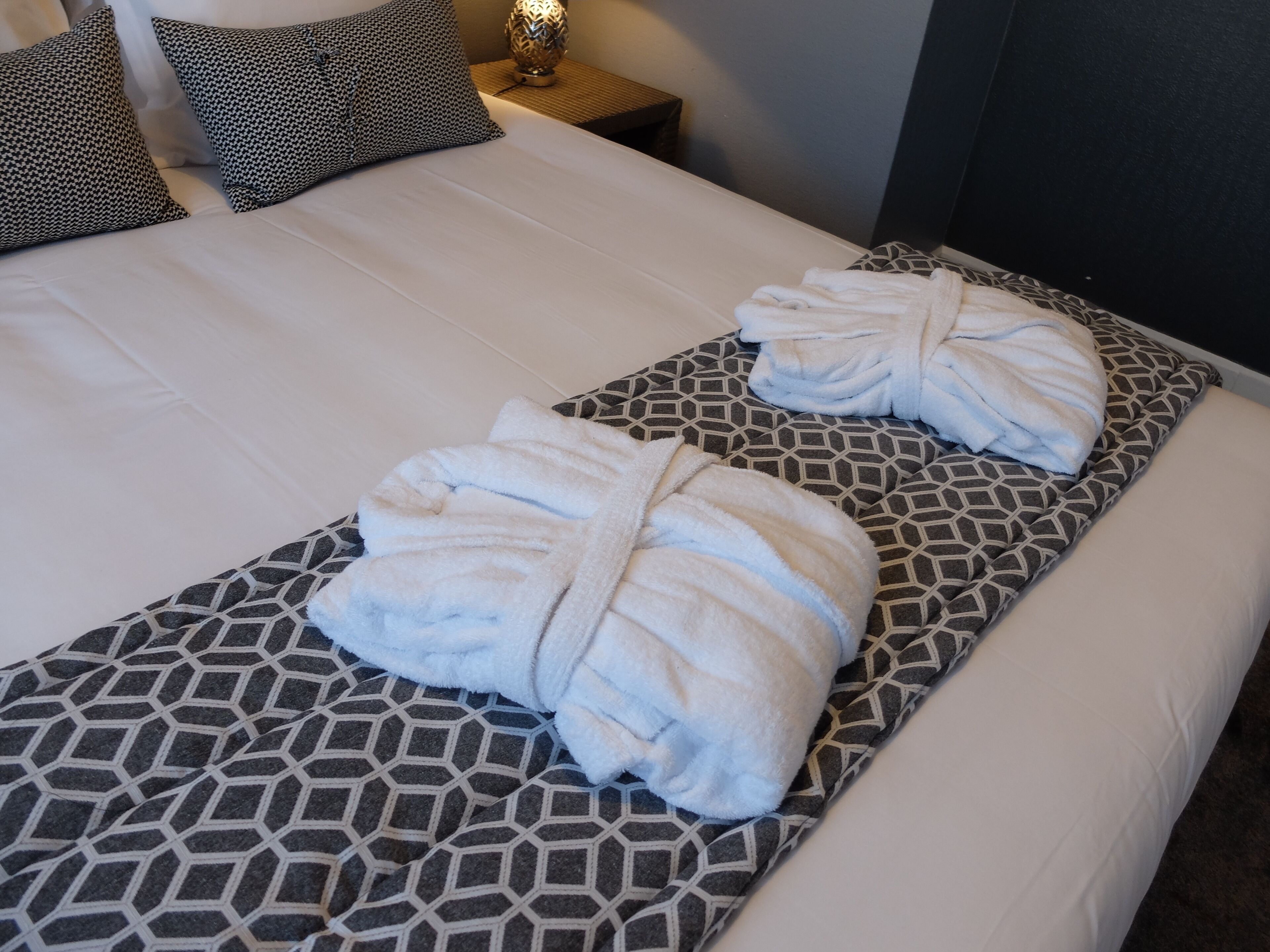 Una cama con una colcha estampada y dos toallas dobladas encima.