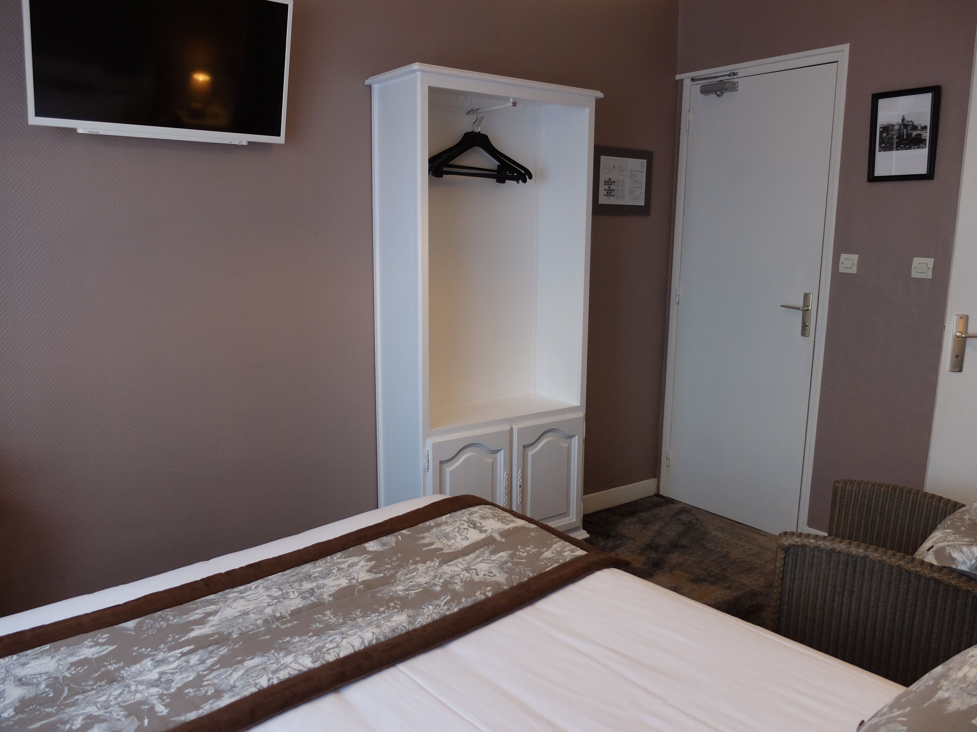 A bedroom with a bed, a wardrobe, a chair, and a door.