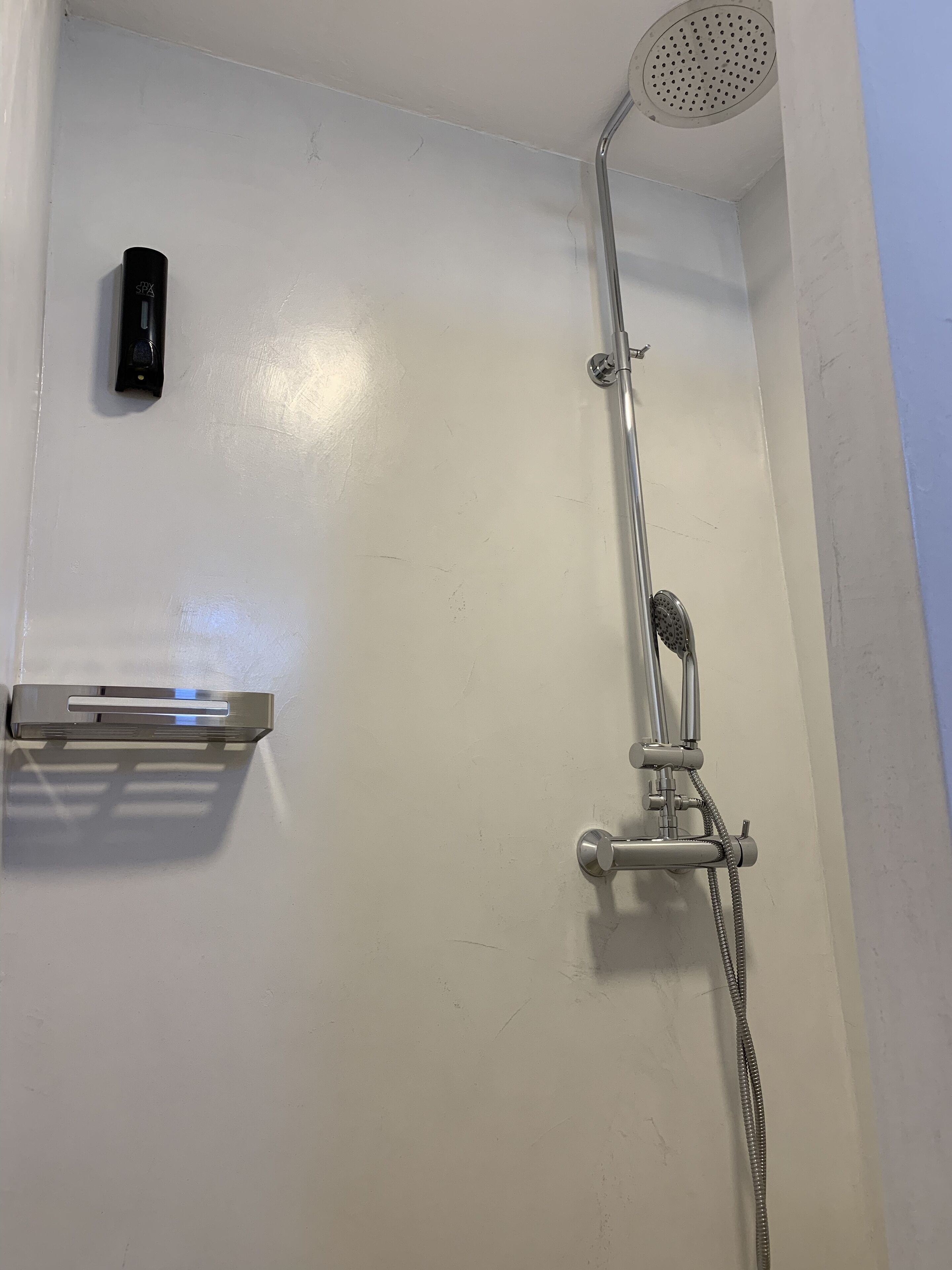 A shower with a handheld showerhead and a handheld soap dispenser.