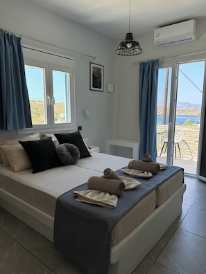 Un dormitorio con cama, cortinas, lámpara colgante, equipo de aire acondicionado y vistas al exterior.