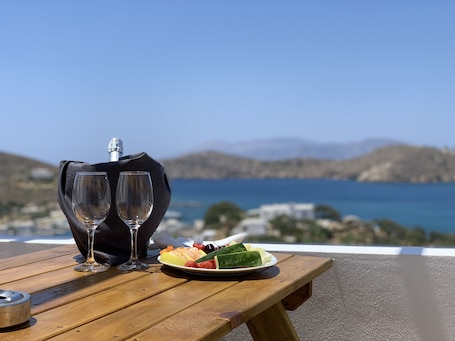 A wooden table with two empty wine glasses, a plate of fruit, and a bottle of champagne.
