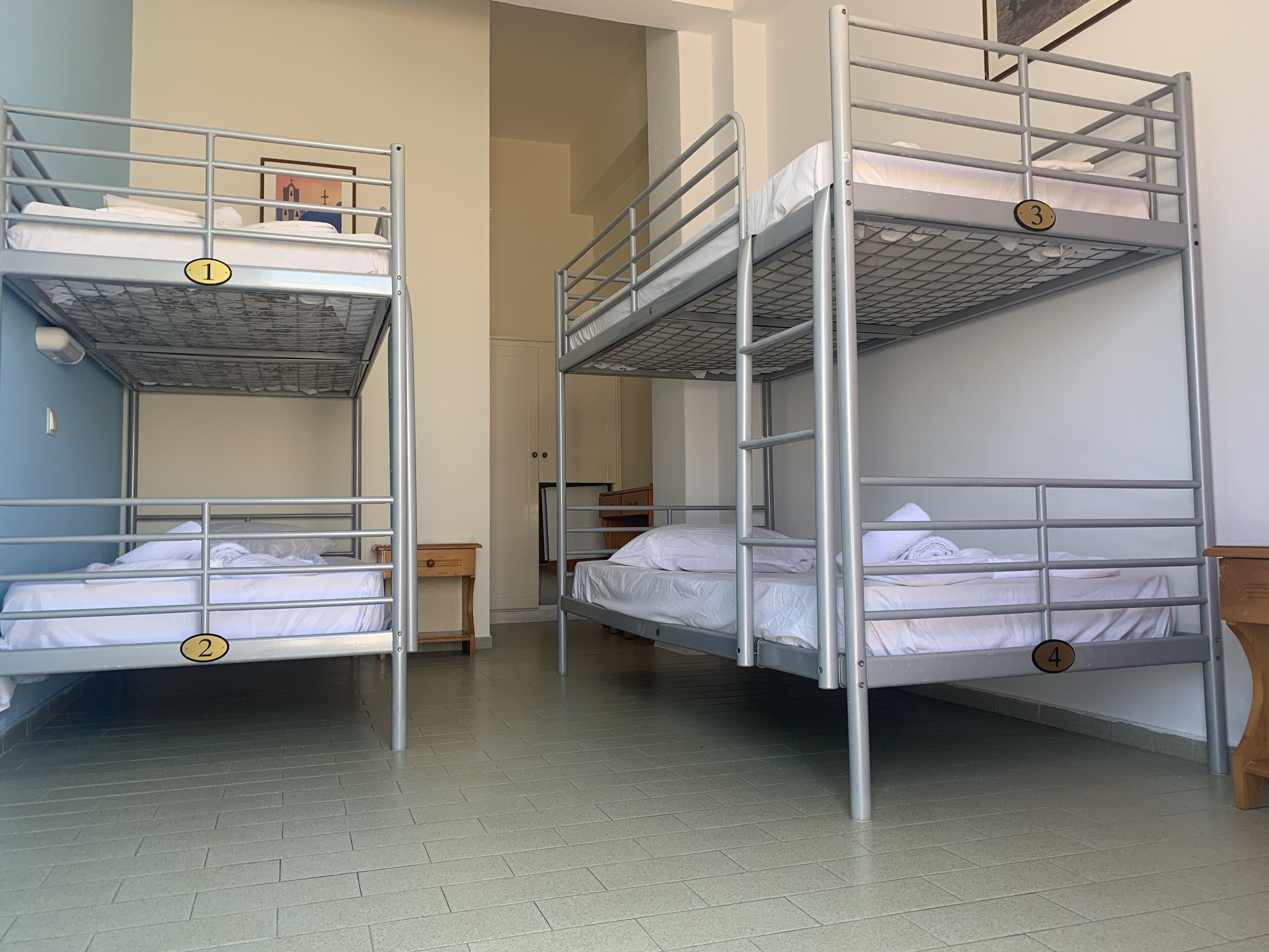 A dormitory with four bunk beds, each marked with a number. There is a small wooden table between the beds.