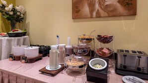 Mesa de buffet con distintos alimentos, un cuadro en la pared y un tostador.