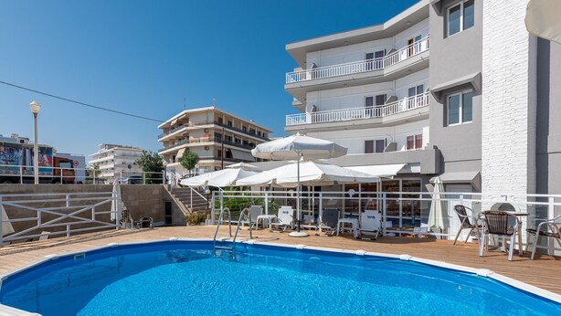 Piscina con tumbonas y sombrillas, rodeada por una terraza de madera.
