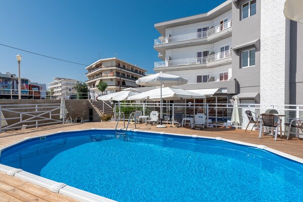 Una piscina al aire libre de temporada, sombrillas