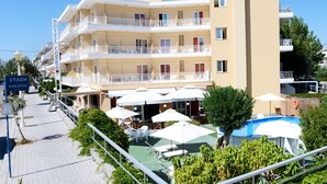 Un hotel con varios balcones, mobiliario exterior y una piscina.