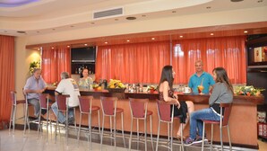 Zona de bar con mostrador, taburetes y una pantalla de televisión.