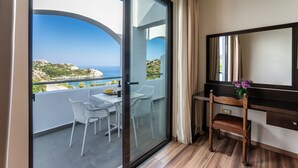 A balcony with a glass door, white chairs, a small table, and a wooden chair. - Ladiko Suites Faliraki  (Rhodes)