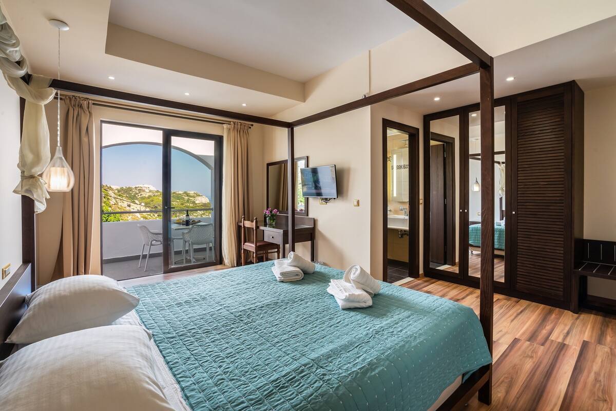 Une chambre d’hôtel avec un grand lit, un bureau, une télévision et un balcon avec vue.