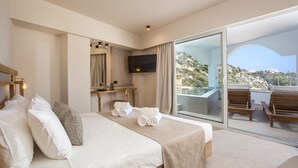 A modern hotel room with a bed, a TV, a balcony with chairs, and a view of the landscape. - Ladiko Suites Faliraki  (Rhodes)