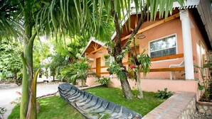 A house with a garden, a boat, and a palm tree. - Palm Inn Hotel (Port-au-Prince)
