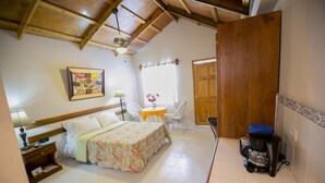 A small, cozy room with a bed, a table with chairs, a coffee maker, and a door. - Palm Inn Hotel (Port-au-Prince)
